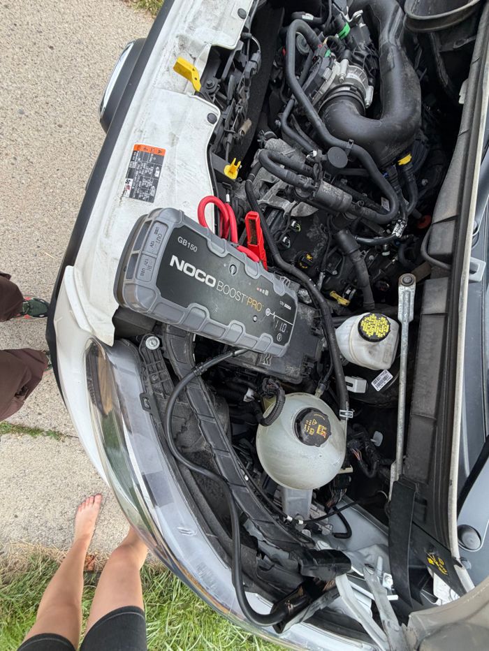 Portable jump starter and cables in a vehicle engine bay