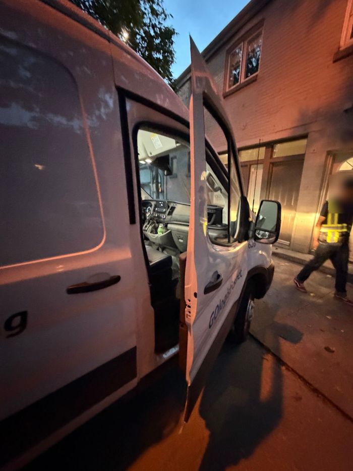 Open driver door of a white van at dusk