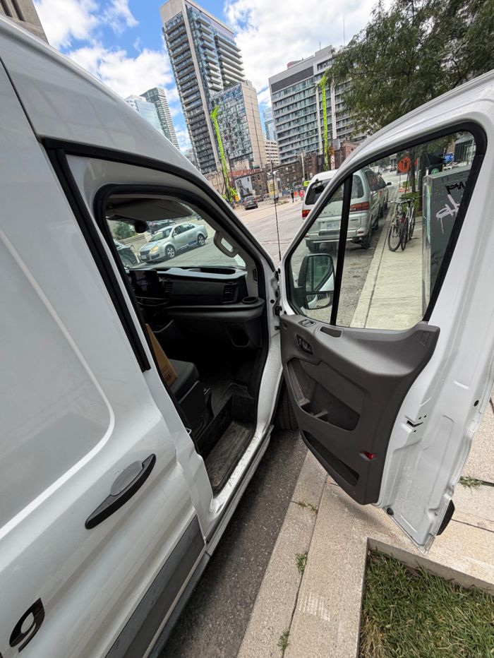 Open driver door and interior of a white van in daylight