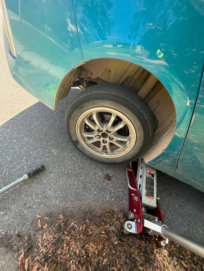 Rear wheel of a blue vehicle with a red jack and service tools