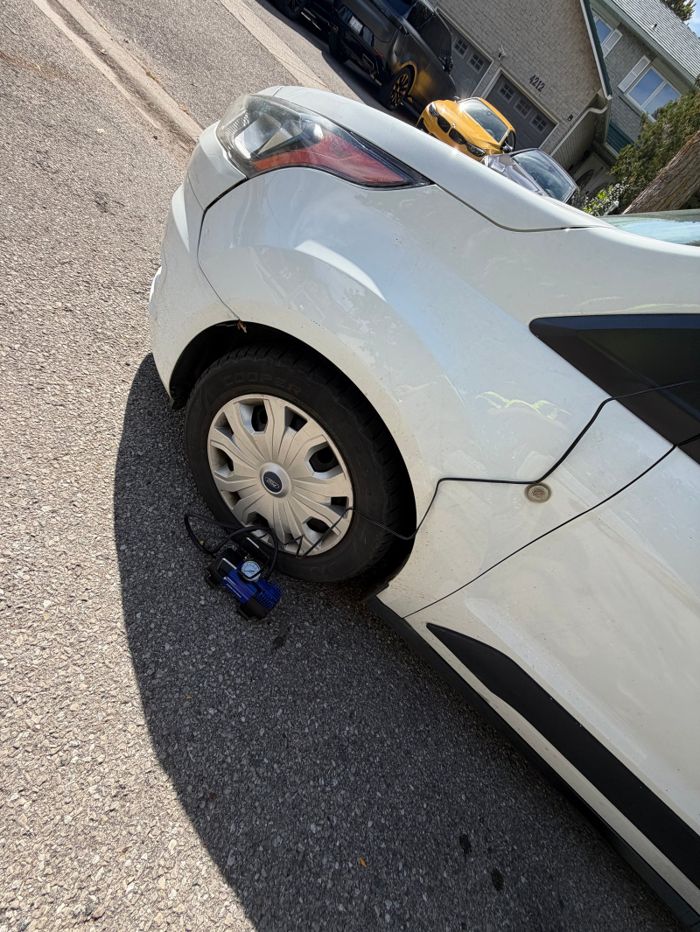 Wheel of a white car with service equipment on the ground